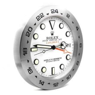 A Rolex wall clock styled like an Explorer II watch, featuring a white dial, black markings, Mercedes hands, a red GMT hand, and a date display.
