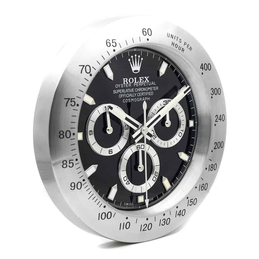 Reloj de pared inspirado en el Rolex Cosmograph Daytona con esfera negra y bisel plateado.