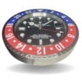 Close-up of a Rolex GMT-Master II wall clock with a red and blue bezel, black dial, and white hour markers, showing the time as 10:10:26.