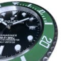 Close-up of a Rolex Submariner watch face showing the black dial, silver and white hour markers, green bezel with white minute markers, and date indication at the 3 o'clock position displaying the 29th.