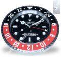 Rolex wall clock designed to resemble a GMT-Master II watch with a black and red outer ring and black dial, featuring white hour markers and hands, along with a date window and a keyhole mounting plate in the corner.