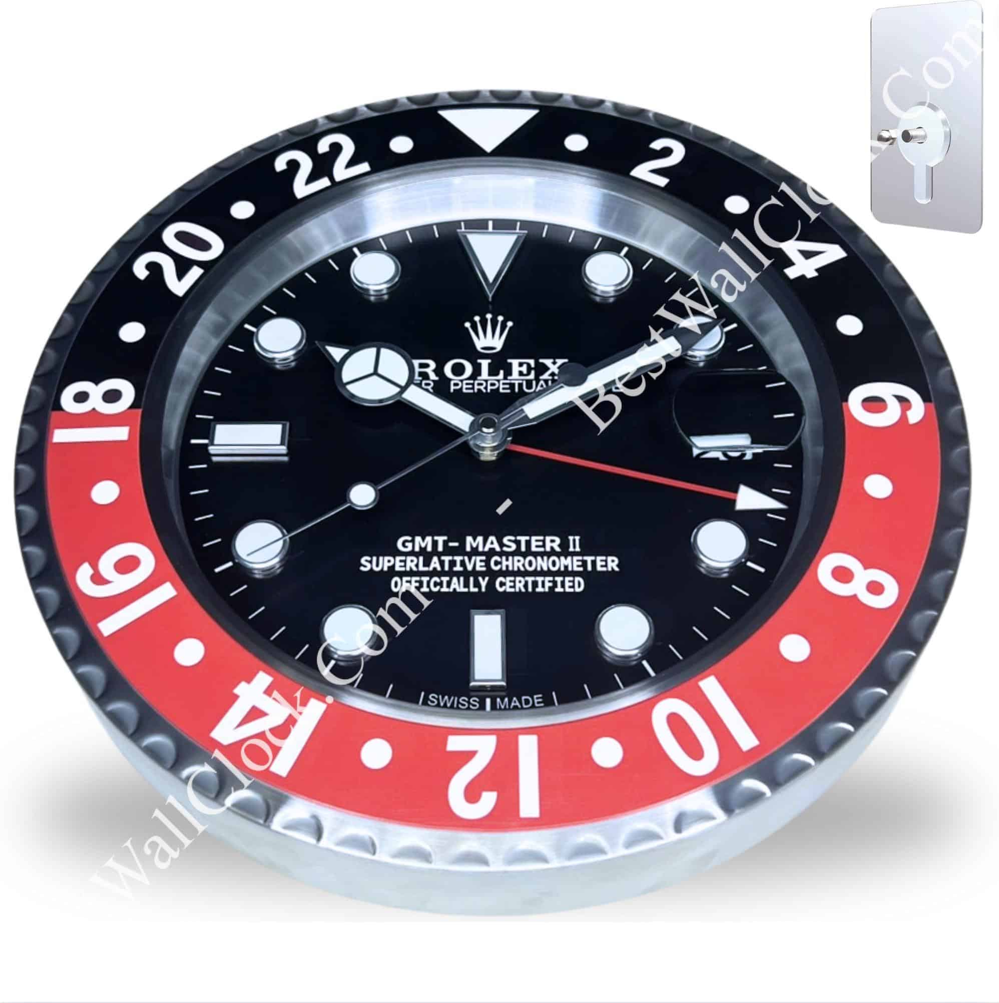 Rolex wall clock designed to resemble a GMT-Master II watch with a black and red outer ring and black dial, featuring white hour markers and hands, along with a date window and a keyhole mounting plate in the corner.