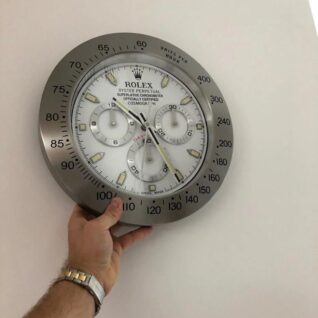 Rolex Daytona wall clock with a white dial, black subdials, and a black tachymeter bezel.