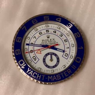 Close-up of a Rolex Yacht-Master II watch face with a blue and silver bezel, white dial, blue and red hands, and black numerals marked from 1 to 10 and 0 to 60 on a smaller inner circle.