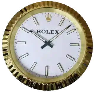 Round wall clock with a gold toothed rim, white face, black rectangular hour markers, and black hour and minute hands showing the time at 10:08.