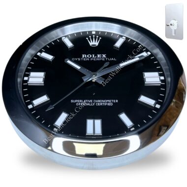 Rolex wall clock with a black dial, silver hour markers and hands, and a polished silver frame, featuring the text 'ROLEX OYSTER PERPETUAL' and 'SUPERLATIVE CHRONOMETER OFFICIALLY CERTIFIED' on the face, with a small key on a metal plate shown in the corner for winding or setting the clock.