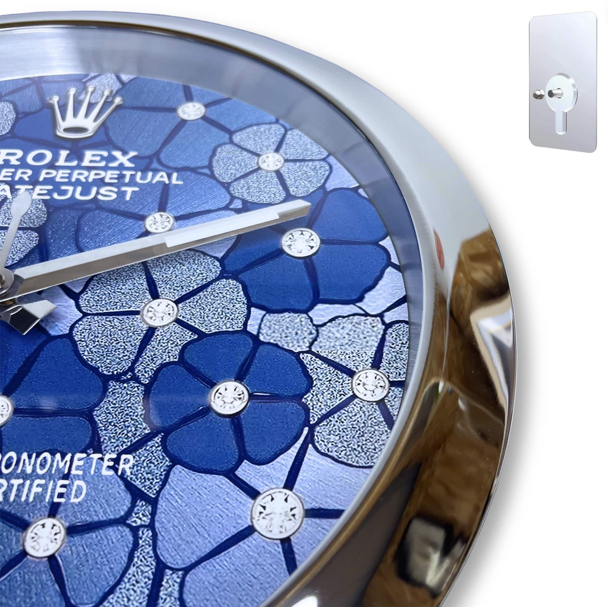 Close-up of a Rolex watch face with a blue floral pattern and diamond hour markers, surrounded by a shiny metallic bezel.