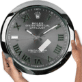Large Rolex Oyster Perpetual Datejust wall clock with silver and black face, green Roman numerals, and a chrome frame, held by two hands on either side
