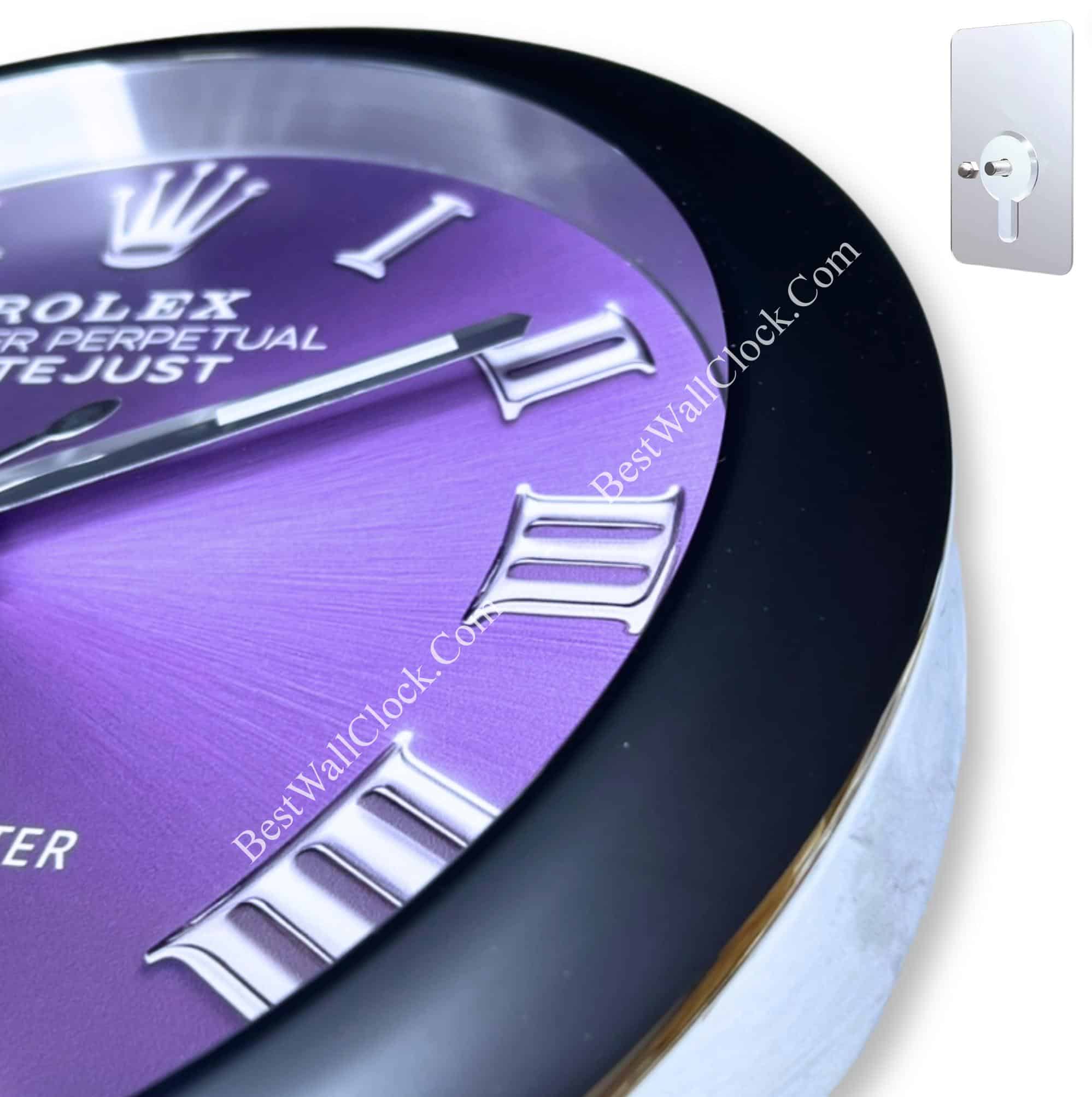 Close-up of a purple Rolex-themed clock face with silver Roman numerals and black and silver hands, featuring a black outer rim and a silver side, accompanied by a small silver keyhole wall mount on a white background.