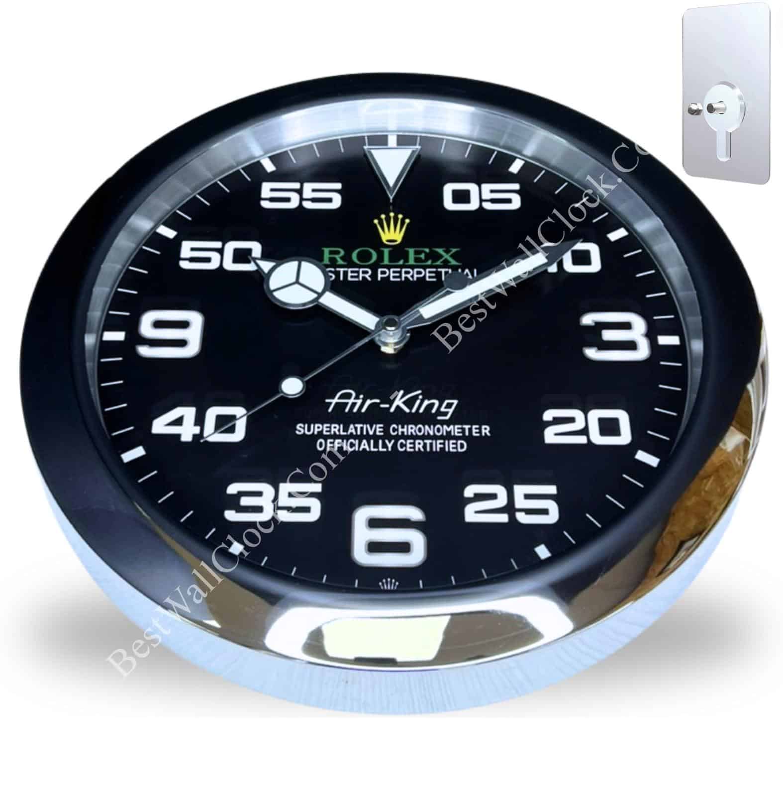 Round wall clock designed like a Rolex Air-King watch face with black dial, white numerals and markings, and silver trim, showing the time as 9:10:40, mounted on a white background with a metal keyhole plate in the upper right corner
