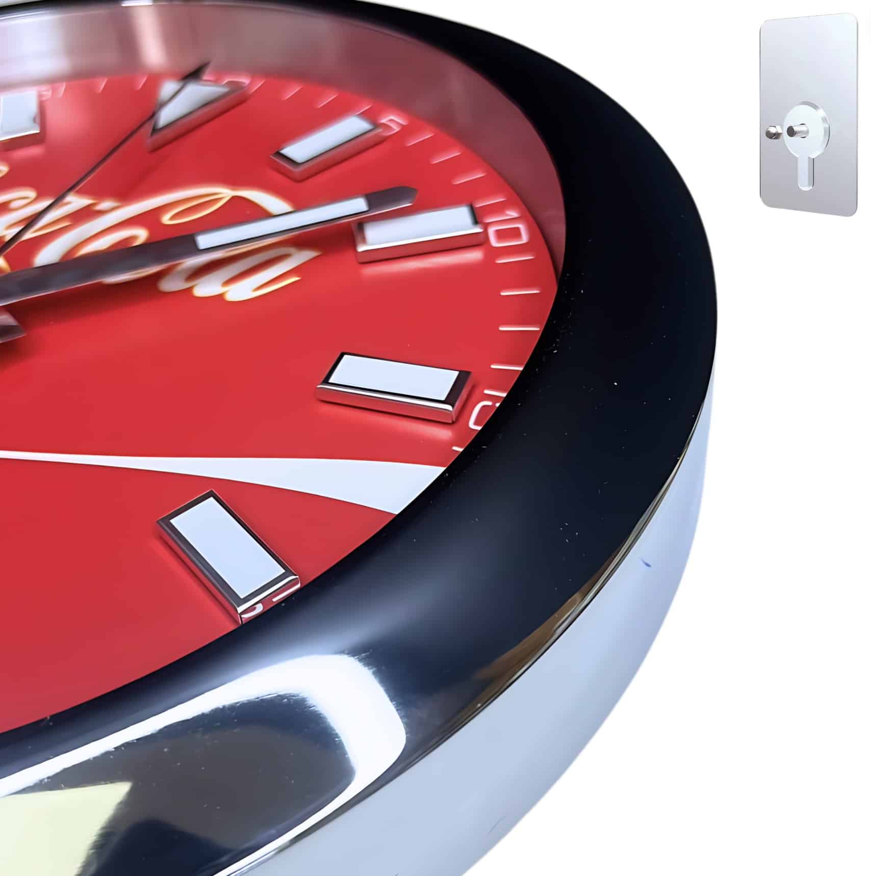 Close-up view of a red Coca-Cola branded wall clock with white hour markers and silver hands, featuring a shiny black and silver frame against a white background.