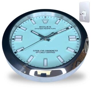 Wall clock designed like a Rolex Oyster Perpetual watch with black frame, light blue face, silver hour markers, and black hands showing time 10:09:40, with a metal adhesive mount in the corner.
