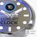 Close-up of a luxury metal clock face showing white and black hour, minute, and second hands over circular and rectangular hour markers, with blue and black branding saying 'Luxury Metal Clocks, No tic - No tac - So chic' and a certified quality badge in the corner.