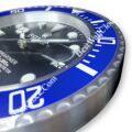 Close-up view of a blue and silver Rolex wall clock designed to resemble a Rolex Submariner watch face with detailed hour markers and date display.