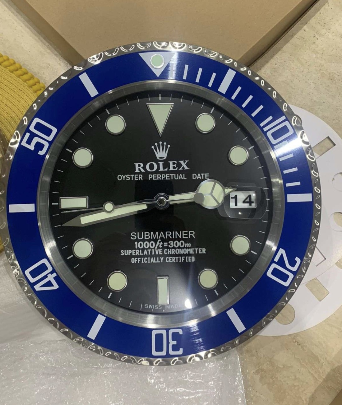 Close-up of a Rolex Submariner watch face with a blue bezel showing the date as 14