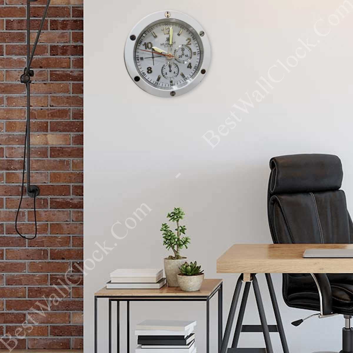 A modern office space with a black chair, wooden desk, potted plant, stacked books, and a round wall clock set against a brick and white wall backdrop.