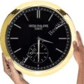 rolex well clock Patek Philippe wall clock with black face, gold rim, and two hands being held by two hands