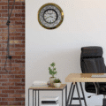 rolex well clock world time wall clock with gold frame hanging on white wall above desk and black office chair in modern room with brick accent wall and small plants on side table