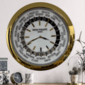 World clock with gold frame showing multiple time zones and marked cities, featuring a white face and gold hour markers, with the text 