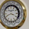 Close-up of a Patek Philippe Genève world clock with gold hour markers and hands, surrounded by a circular list of international city names and a 24-hour day-night indicator ring.