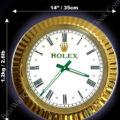 Rolex well clock featuring a round white dial with black Roman numerals and green hands, set in a gold bezel, with measurements 14 inches (35 cm) diameter and weight 1.2 kg (2.6 lbs) indicated around it