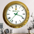 rolex well clock featuring a gold-framed wall clock with Roman numerals and green hands, displayed above a tabletop with a small clock, a mug, and decorative plants, rolex well clock