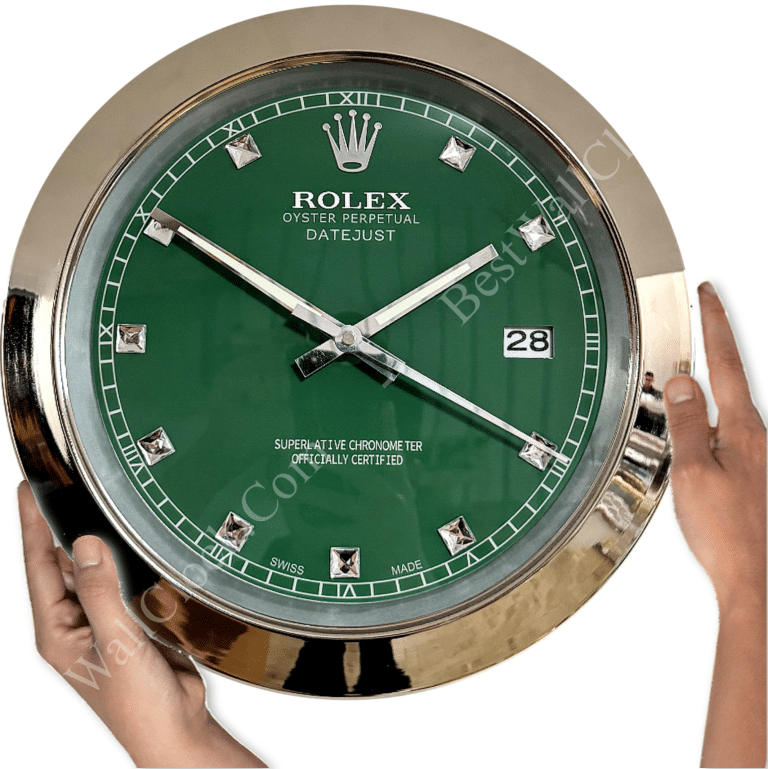 Rolex well clock featuring a green face with silver hour markers and hands, a date window at 3 o'clock, and hands holding the clock by its shiny silver bezel.