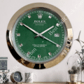 rolex well clock featuring a green face with silver hour markers and hands, set in a metallic gold frame, mounted on a wall above a shelf with a small round clock and decorative items