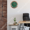 rolex well clock green and gold wall clock hanging on white wall above small table with plants in a modern office setting