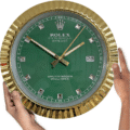 Rolex well clock featuring a green face with diamond hour markers, gold fluted bezel, date display at 3 o'clock, and two hands held by two hands on either side