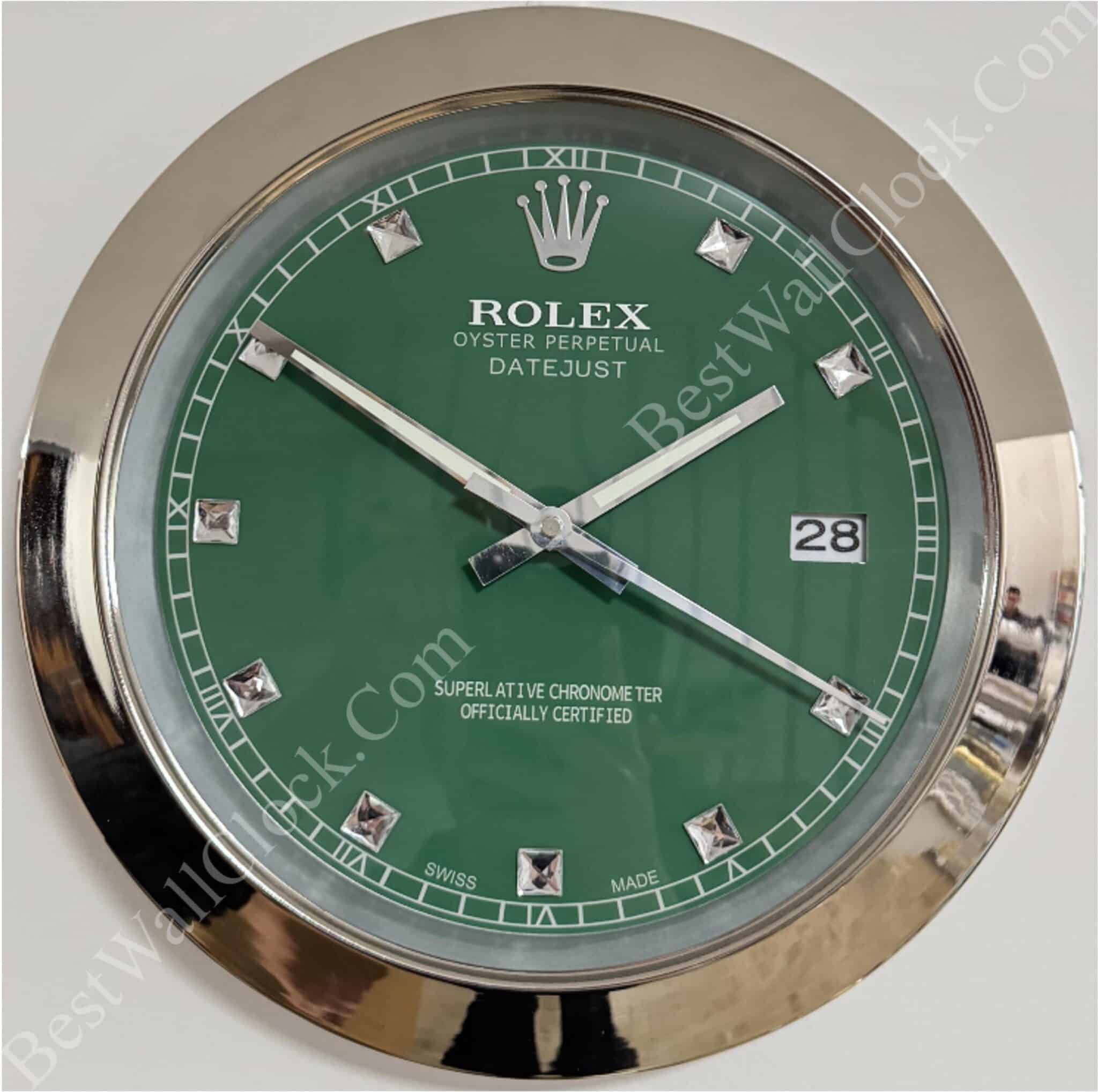 rolex well clock showing green face with silver hour markers and hands in a round chrome frame indicating time at 10:11:40 with date window at 3 o'clock