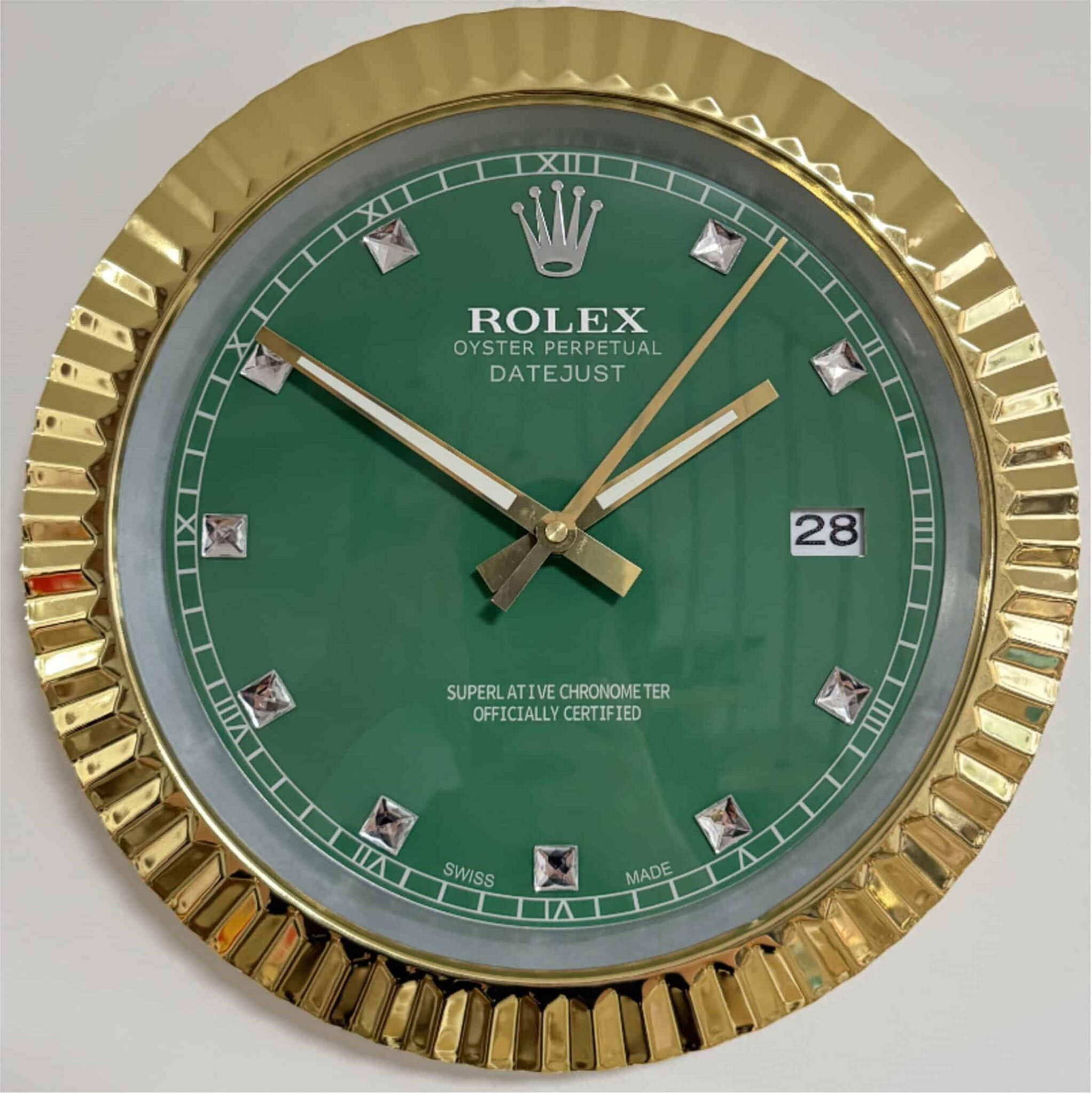 Close-up of a green dial wall clock styled like a Rolex wristwatch with gold fluted bezel, diamond-shaped hour markers, and date window at 3 o'clock, described as a rolex well clock