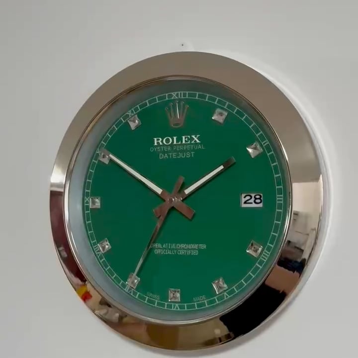Round wall clock designed like a Rolex Datejust watch face with green dial, silver hour markers, and silver frame, showing the time as 10:10:33 and displaying the date as 28