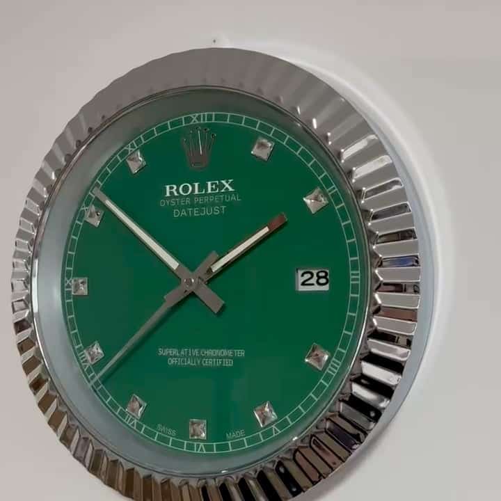 Close-up of a green Rolex Oyster Perpetual Datejust wristwatch face with silver hour markers and hands, showing the date as 28, against a white background.