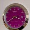 Close-up of a Rolex Oyster Perpetual Datejust watch with a magenta dial, silver hour markers, silver hands, and a date display showing the 27th, set in a shiny silver bezel.
