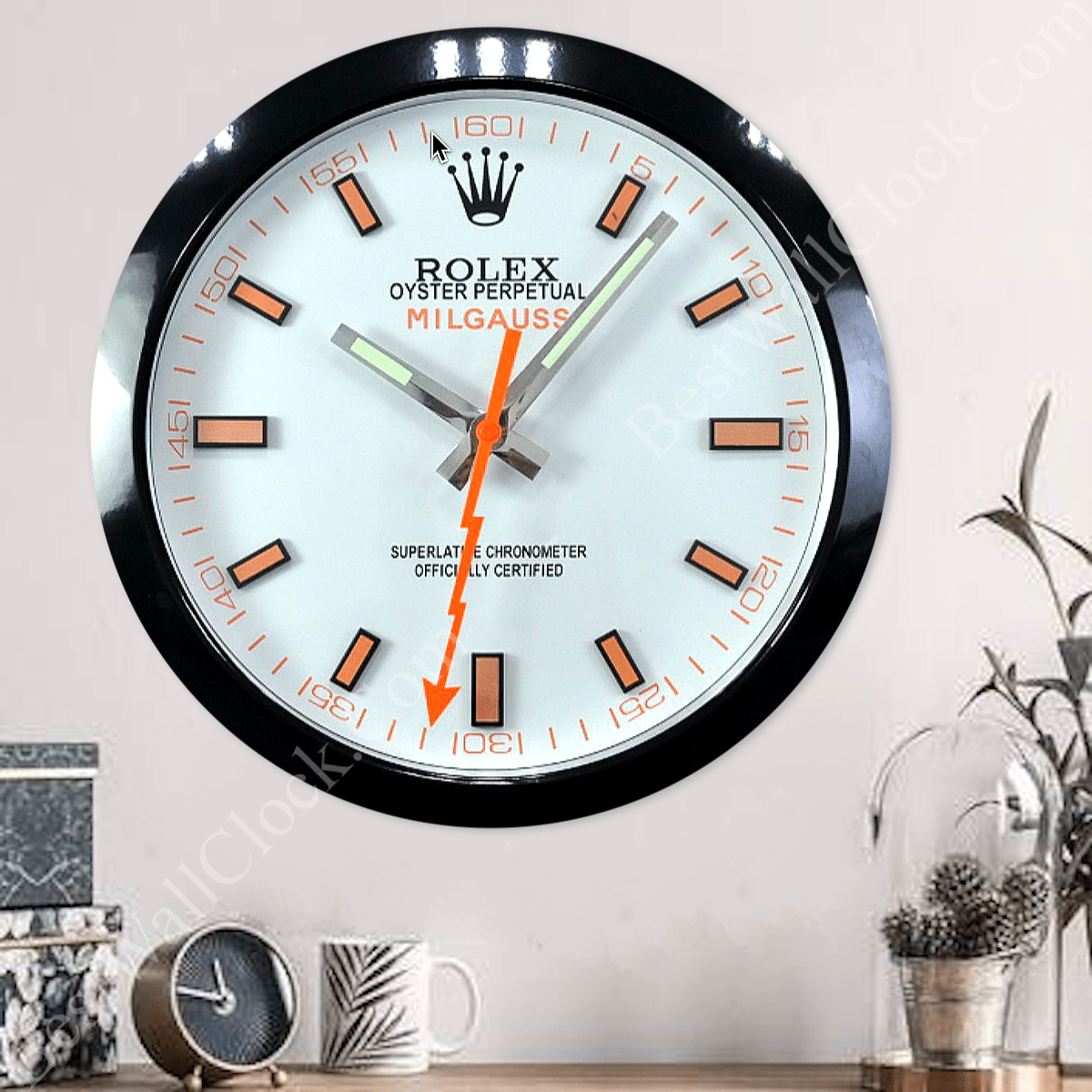 rolex well clock featuring a wall clock styled like a Rolex Milgauss watch face with orange and black markers and lightning bolt second hand above a wooden surface with decorative objects