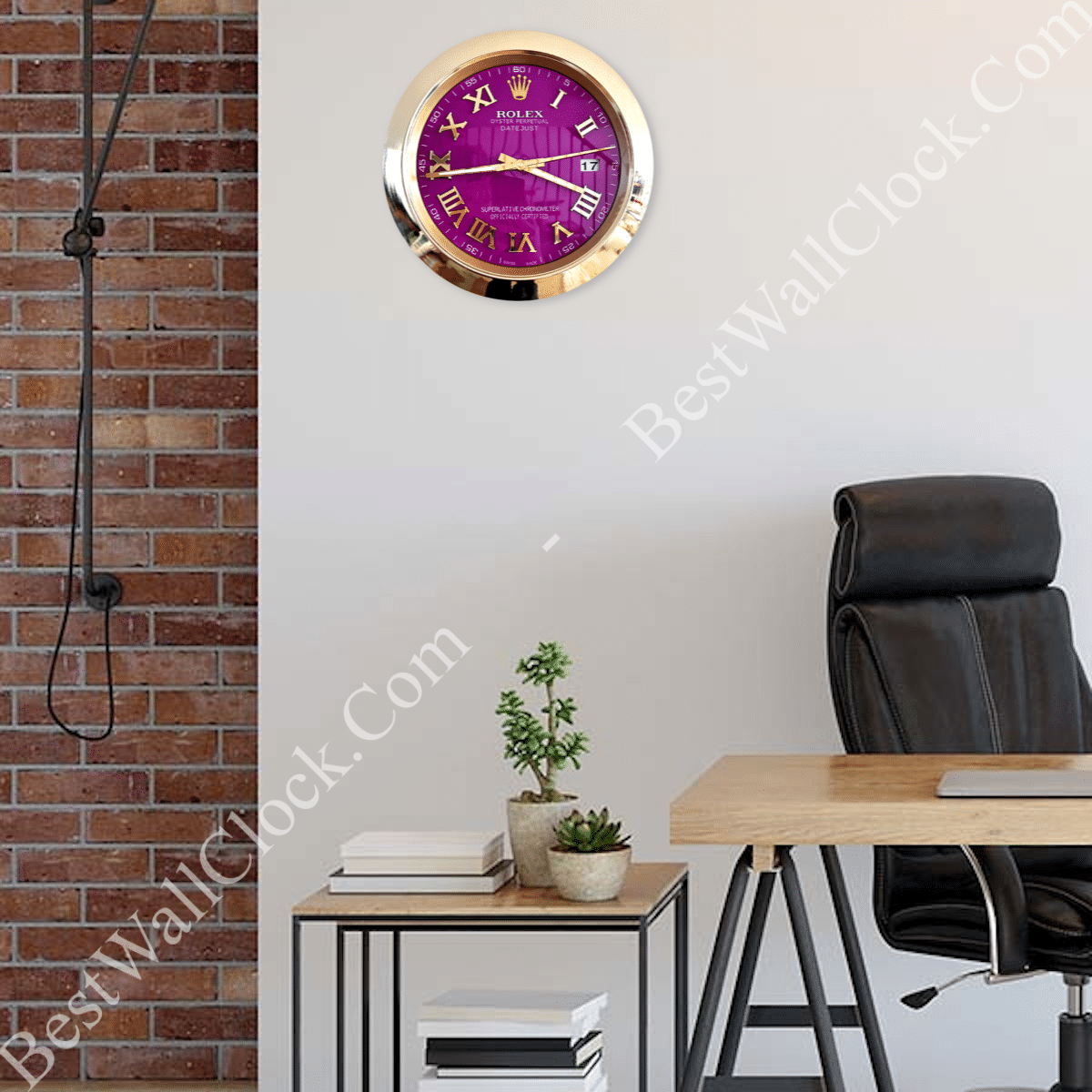 Modern office space with a black leather chair and wooden desk, a side table holding books and two small potted plants, and a wall-mounted clock with a purple face and gold Roman numerals and casing on a light grey wall beside a brick wall section.