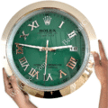 Green Rolex clock with Roman numerals and date display showing the number 18, held by two hands against a white background