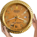 Gold Rolex Oyster Perpetual Datejust wall clock with Roman numerals and a fluted bezel, held by two hands against a white background