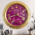 Gold-framed wall clock with a purple face featuring large gold Roman numerals and the brand name Rolex, displaying the time as 8:15 with a date window showing the 17th, mounted on a light grey wall above a wooden surface with a small black clock, a white mug with leaf design, and a glass cloche with pine cones and a green plant.