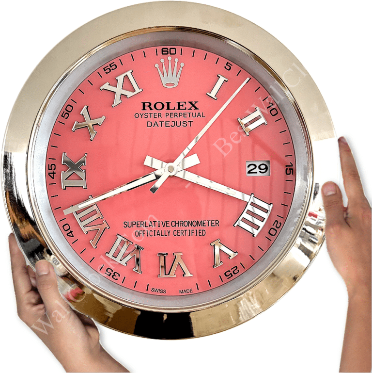Close-up of a Rolex Oyster Perpetual Datejust wall clock with a pink face, silver Roman numerals, and a silver metal frame showing the time at 1:39:06, held by two hands on either side.