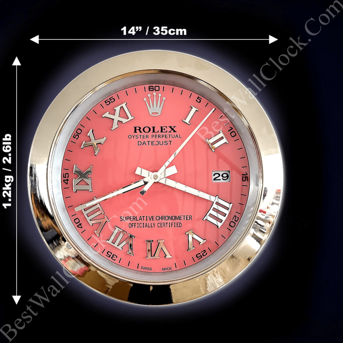 Round wall clock with a gold frame and pink face featuring Roman numerals, minute markers, date window showing 29, and inscriptions reading Rolex Oyster Perpetual Datejust, Superlative Chronometer Officially Certified, and Swiss Made, with dimensions 14 inches (35 cm) diameter and weight 1.2 kg (2.6 lb) indicated by arrows around the clock