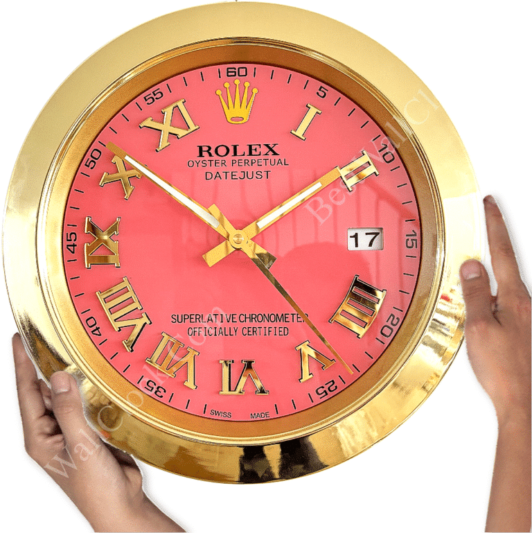Gold-framed wall clock resembling a Rolex watch face with a pink dial, Roman numerals, and showing the date as 17, held by two hands against a white background