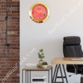 Office interior with a red and gold Rolex wall clock, a wooden desk with a laptop, a black office chair, a side table with books and small potted plants, and a brick wall on the left side.