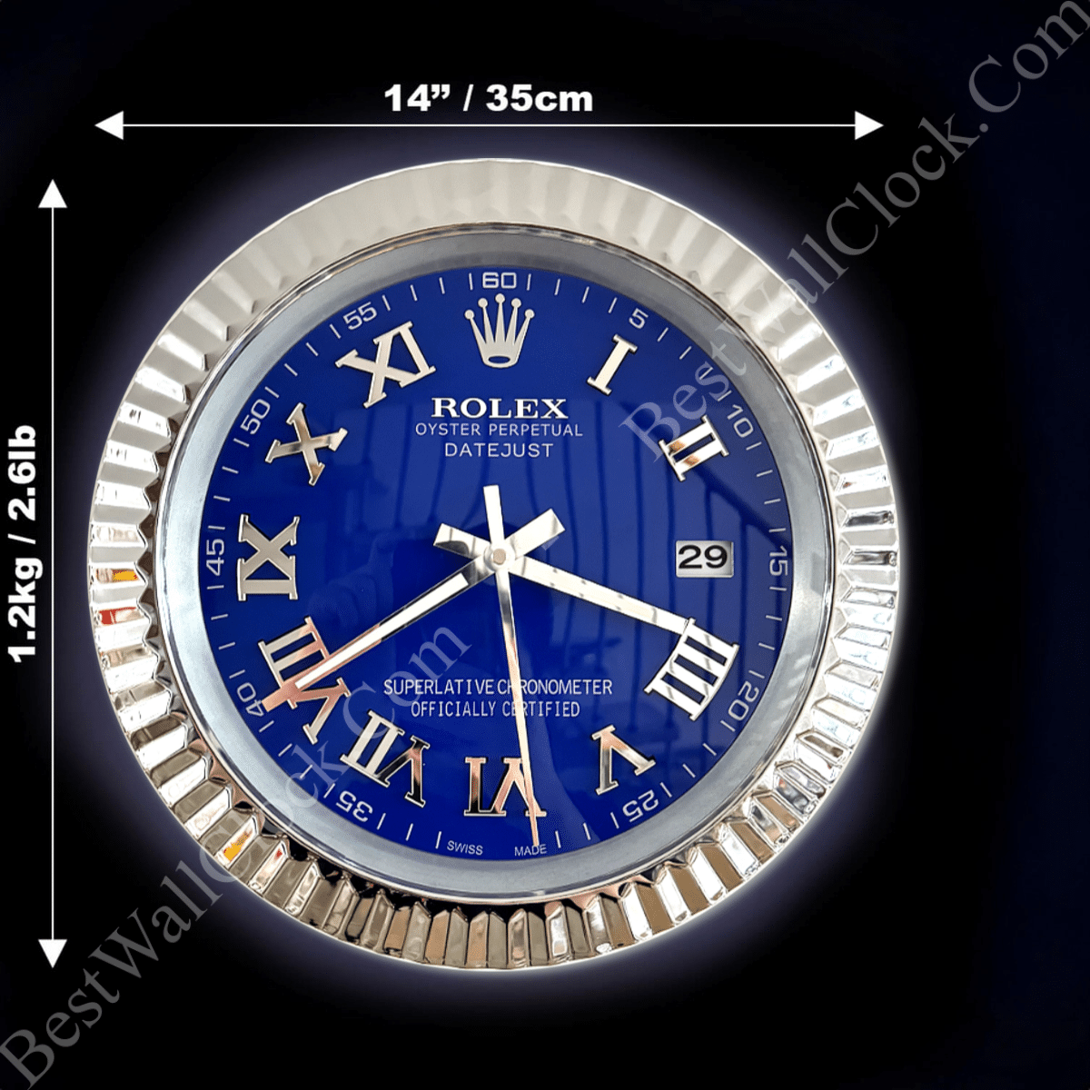 A round Rolex wall clock with a blue face, silver Roman numerals, and silver hands, measuring 14 inches (35 cm) in diameter, with a silver ridged frame weighing 1.2 kg (2.61 lb) on a dark background.
