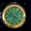Round Rolex wall clock with a green face, gold frame, and white hour markers, showing the time as 3:36:51, with dimensions of 14 inches (35 cm) in diameter and weighing 1.2 kg (2.6 lb) indicated by arrows on a black background.