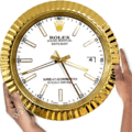 Close-up of hands holding a large gold Rolex wall clock with a white face, gold hour markers, and three gold hands showing the time as approximately 4:43:25, including a date window showing the number 4.