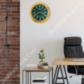 Modern office corner with a black leather chair, wooden desk with a laptop, side table holding books and small potted plants, brick wall on the left, and a green-faced Rolex wall clock with a gold rim above the table.