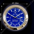 Rolex Sky-Dweller wall clock with a blue dial, white hour markers, and silver hands, featuring date display and a gold-toned frame, shown against a black background with size dimensions of 14 inches (35 cm) in diameter and weight of 1.2 kg (2.6 lb) indicated.