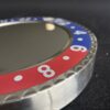 Close-up of a circular metallic object with a red and blue numbered bezel, showing numbers 4, 6, and 8, on a dark surface.